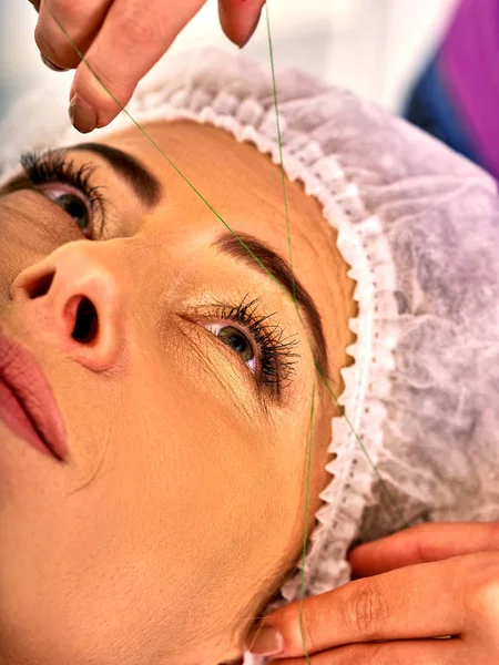 Eyebrow threading of woman middle-aged in spa salon.