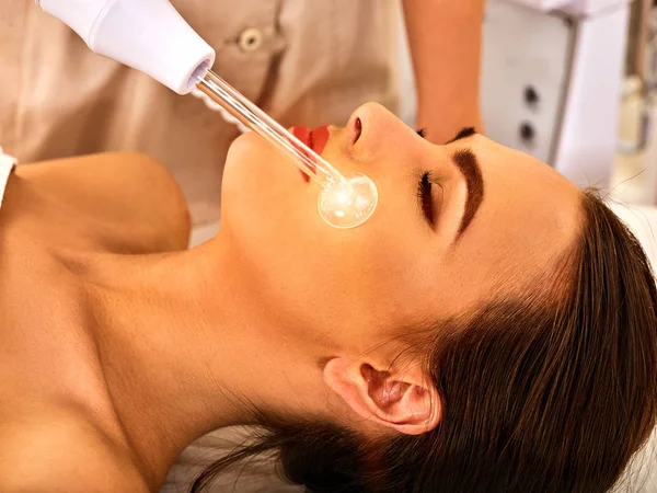 Mujer joven recibiendo masaje facial eléctrico . —  Fotos de Stock