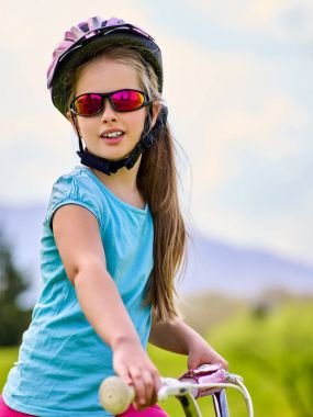 Çocuk gökkuşağı gözlük içinde bisiklet ve kask Park seyahat.
