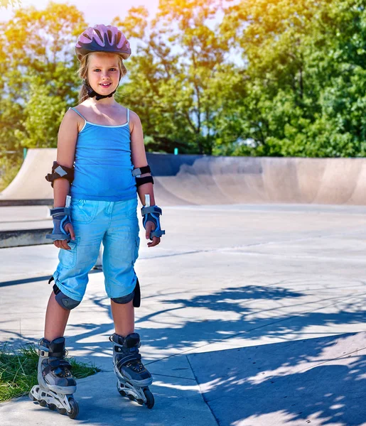 Girl roller in skates park. Child wear safety helmet do sport exercise.