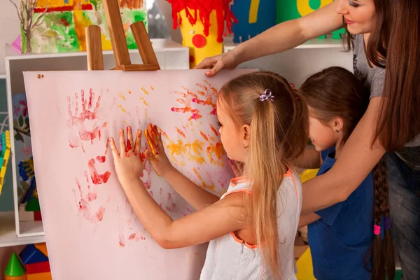 Børn maler finger på staffeli. Gruppe af børn med lærer . - Stock-foto