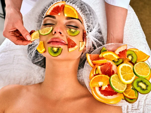 Facial mask from fresh fruits for woman . Beautician apply slices.