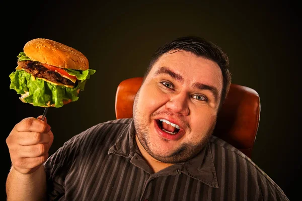Gruby mężczyzna jedzenie fast food hamberger. Śniadanie dla osób otyłych. — Zdjęcie stockowe