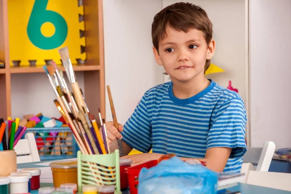 Liten studenter pojke målning i konst skola klass. — Stockfoto