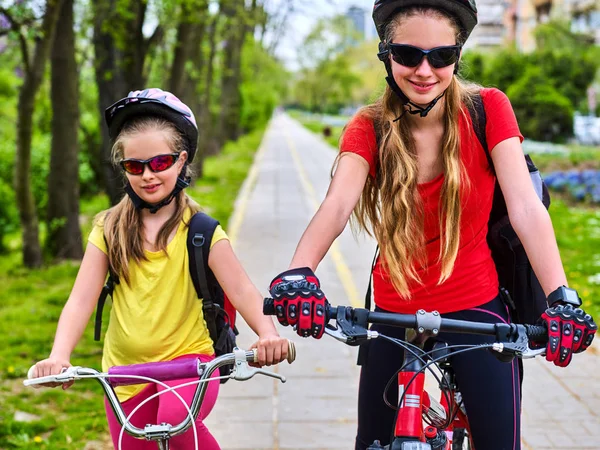 Bicycle path with children. Girls wearing helmet with rucksack .