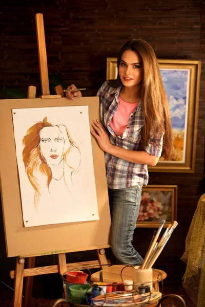 Artist painting on easel in studio. Girl paints portrait of woman with brush. — Stock Photo, Image