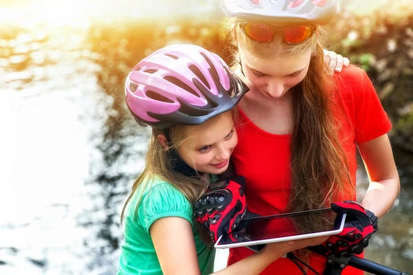 Ποδήλατα ποδηλασία κορίτσι. Τα παιδιά βόλτες με ποδήλατο. Ποδηλάτης υπολογιστή tablet ρολόι. — Φωτογραφία Αρχείου
