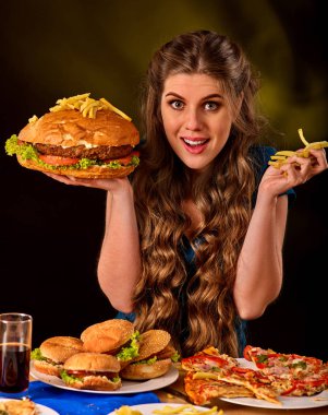 Patates kızartması ve hamburger masada yemek kadın.