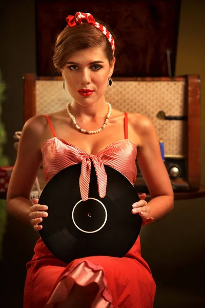 Retro kvinna med musik vinylskiva. Flicka pin-up stil iklädd röd klänning. — Stockfoto