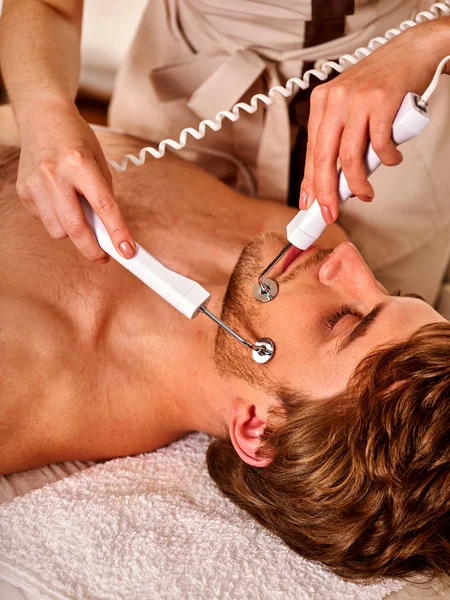De massage van het gezicht man op de salon van de schoonheid. De zorg van de huid van de elektrische stimulatie. — Stockfoto