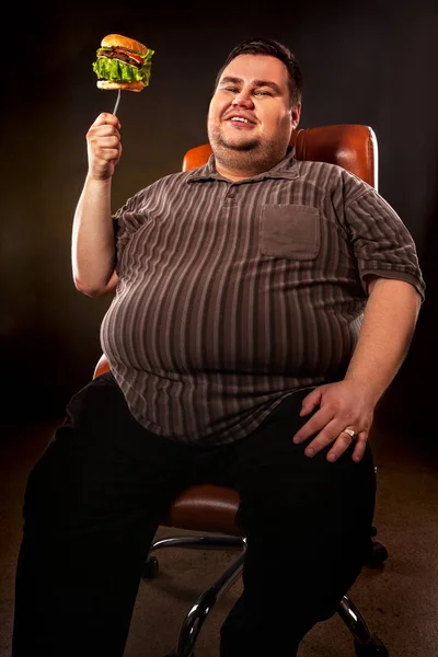 Homem gordo a comer hambúrguer de fast food. Pequeno-almoço para pessoa com excesso de peso . — Fotografia de Stock