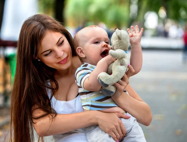 Baby i park utomhus. Snålt med leksak på mammor händer. — Stockfoto