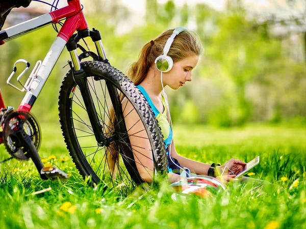 Ποδήλατα, ποδηλασία κορίτσι φοράει ρολόι ακουστικά στο pc δισκίο κοντά ποδήλατο. — Φωτογραφία Αρχείου