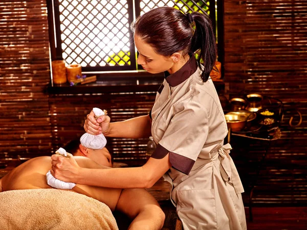 Muž s Ayurveda masáže s bylinkovou horké koule. Terapie v indické léčebné salon. — Stock fotografie