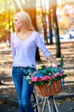 Kadın çiçek sepeti yaz park açık ile bisiklet üzerinde.