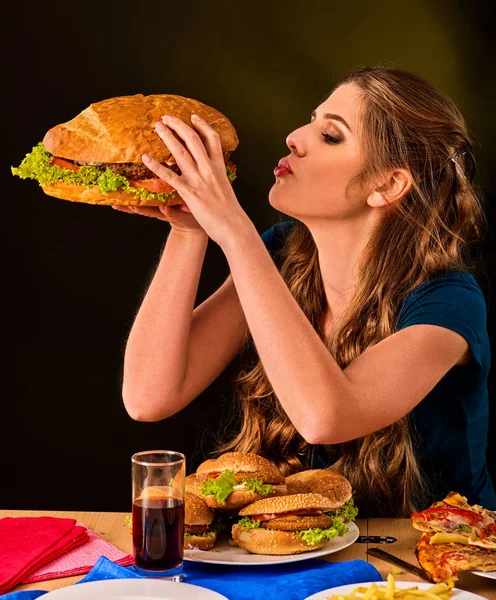 Kvinna äta pommes frites och hamburgare med pizza. — Stockfoto