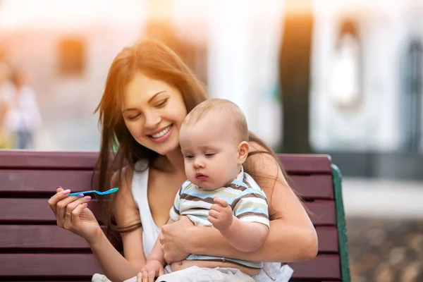 Cucchiaio di alimentazione del bambino dalla madre nel parco all'aperto. Tonalità colore . — Foto Stock