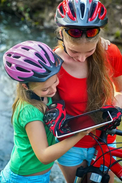 Barn som reser cykel i sommar park. Cyklist klocka på tablet PC. — Stockfoto