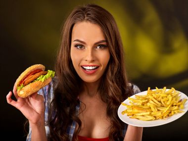 Patates kızartması ve hamburger masada yemek kadın.