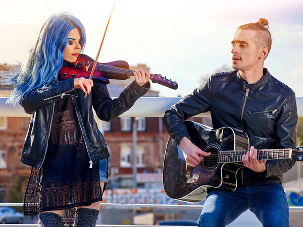 Фестивальная музыкальная группа. Друзья играют на гитаре и скрипке в городском парке
.