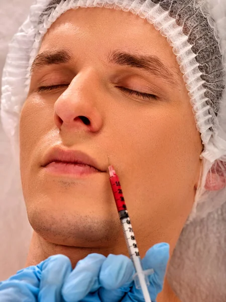 Dermal fillers of man in spa salon with beautician.