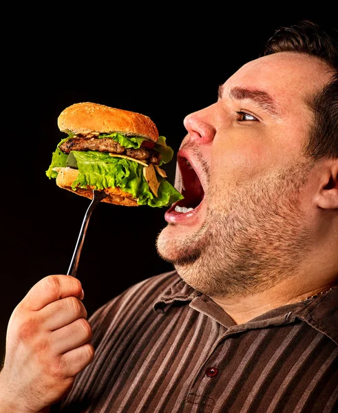 Un ciccione che mangia hamberger da fast food. Colazione per persona in sovrappeso . Immagini Stock Royalty Free