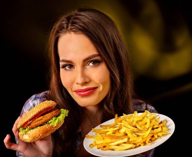 Patates kızartması ve hamburger masada yemek kadın.