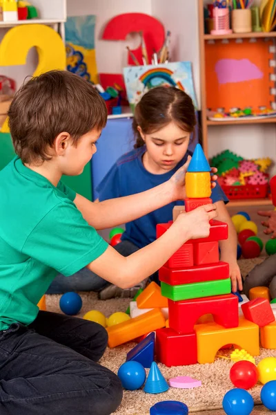 Los niños construyen bloques en el jardín de infantes. Grupo niños jugando juguete piso  . — Foto de Stock