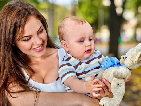 Baby in park buiten. Kind met speelgoed op moeders handen. — Stockfoto