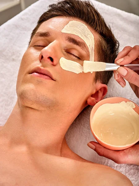 Masque facial boue de l'homme dans le salon de spa. Massage du visage  . — Photo