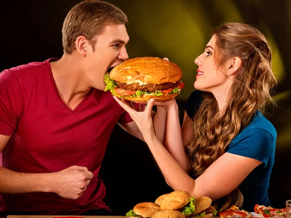 Пара ест фаст-фуд. Мужчина и женщина лечат гамбургер  . — стоковое фото