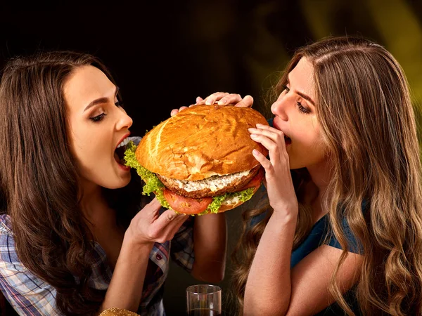 Mulheres a comer fast food. Gils comer hambúrguer com presunto  . — Fotografia de Stock