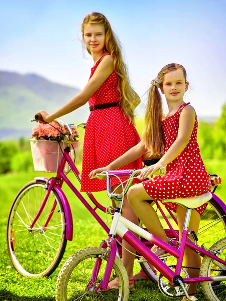 Chica con lunares rojos vestido monta bicicleta en el parque . — Foto de Stock