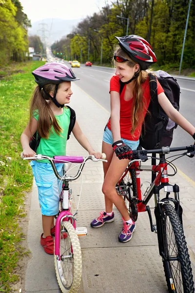 Flickor barn cykling gul cykel körfält. Det finns bilar på vägen. — Stockfoto