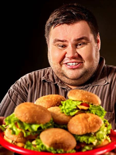 Fat man eating fast food hamberger. Breakfast for overweight person.