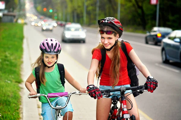 Mädchen, die auf dem gelben Radweg fahren. Es sind Autos auf der Straße. — Stockfoto