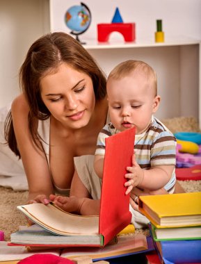 Çocuk ve anne çocuk yerde yatarken bebek ve kitap okumak.