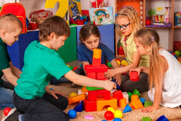 Crianças construindo blocos no jardim de infância. Grupo de crianças jogando chão de brinquedo . — Fotografia de Stock