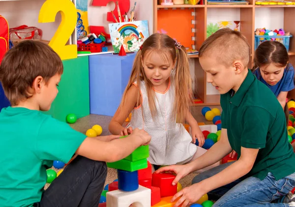 Дети строят блоки в детском саду. Групповые дети играют в игрушки  . — стоковое фото