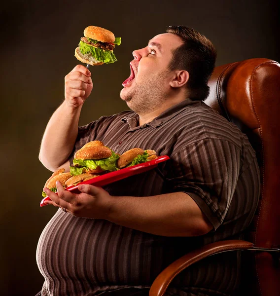 Fat man eating fast food hamberger. Breakfast for overweight person.