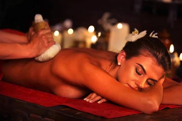 Spa hediyeler kadının spa salonda masaj. Kadın topu terapi sıcak otlar var. — Stok fotoğraf