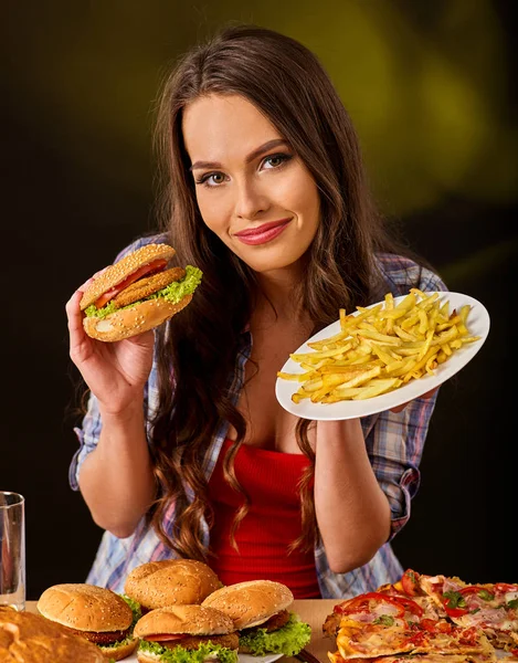 Mujer comiendo papas fritas y hamburguesa en la mesa . —  Fotos de Stock