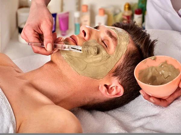 Máscara facial de barro de hombre en el salón de spa. Masaje facial  . — Foto de Stock