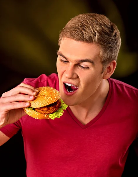 Un homme mange un hamburger. Fastfood et concept de malbouffe . — Photo