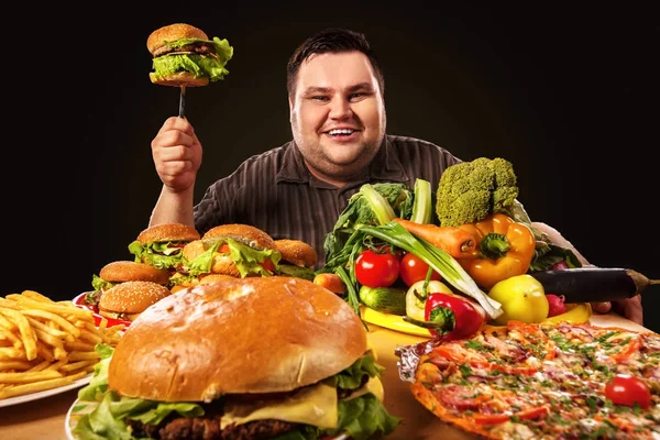 Dieta homem gordo faz escolha entre alimentos saudáveis e não saudáveis . — Fotografia de Stock