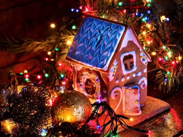 Gingerbread houses with christmas lights string on wooden table. — Stock Photo, Image