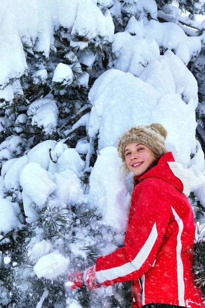 Girl wearing winter clothes shakes off from branches of trees. — Stock Photo, Image