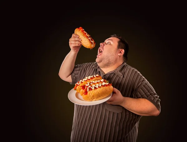 Gruby mężczyzna jedzenie fast food hot doga. Śniadanie dla osób otyłych. — Zdjęcie stockowe