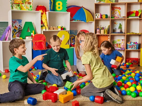 Crianças construindo blocos no jardim de infância. Grupo de crianças jogando chão de brinquedo  . — Fotografia de Stock
