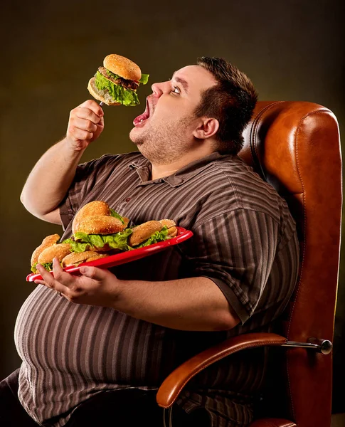 Fat man eating fast food hamberger. Breakfast for overweight person. Royalty Free Stock Images